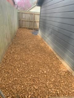 A backyard with a wooden fence and a pile of mulch.