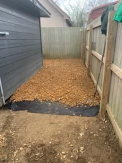 A backyard with a wooden fence and a pile of dirt.