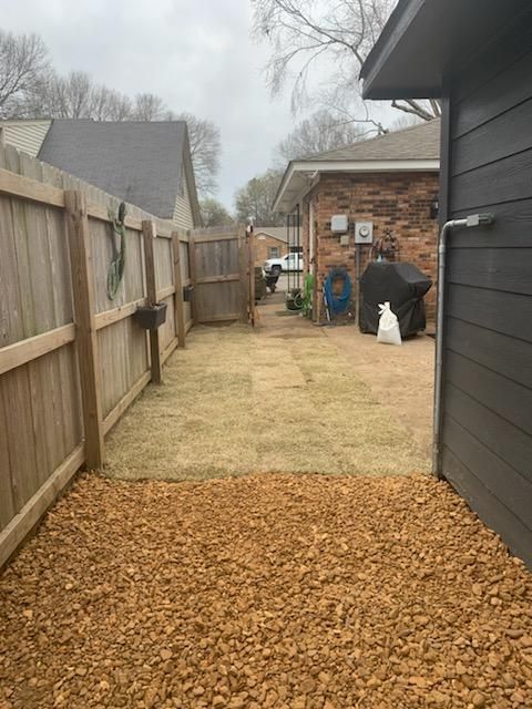 A backyard with a wooden fence and gravel.