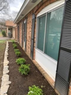 A brick house with a row of plants in front of it.