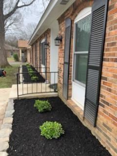 A brick house with a black mulch bed in front of it.