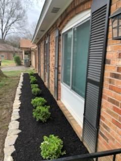 A brick house with a row of plants in front of it.