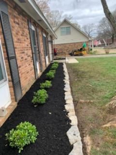 A brick house with a black mulch bed in front of it.