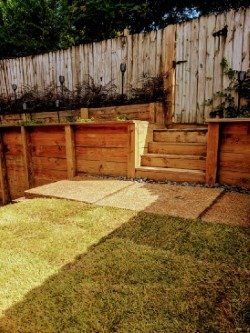 Wooden terraced backyard with steps and fence.