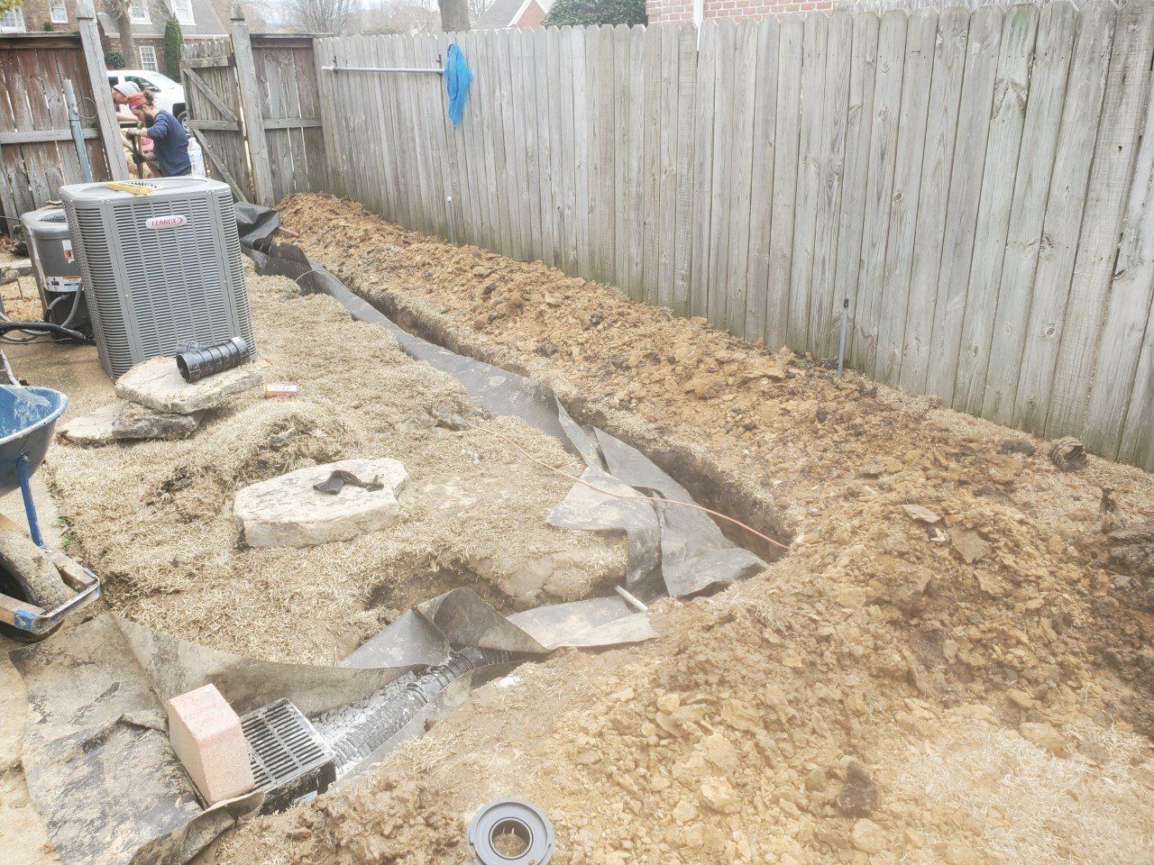 A trench dug along a wooden fence; work in progress.