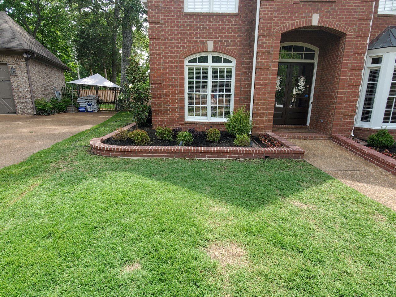Brick house with a small garden bed and green lawn in front.