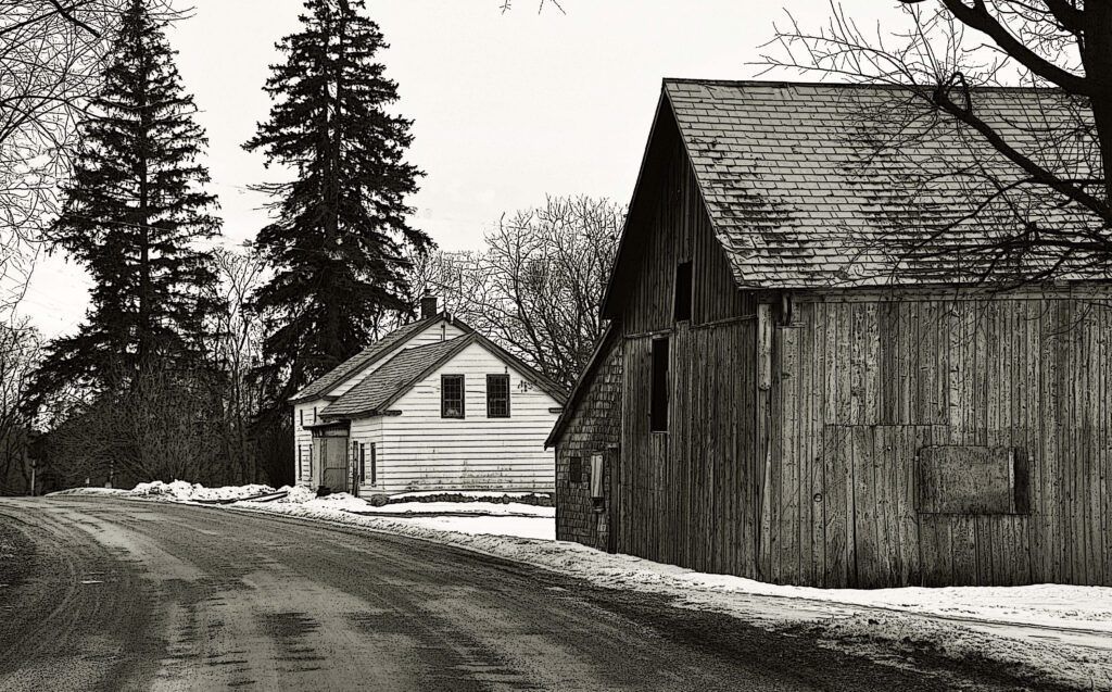 a black and white photo of a house and a barn