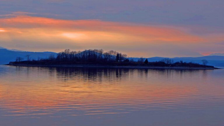 a small island in the middle of a lake at sunset,  Law Island 