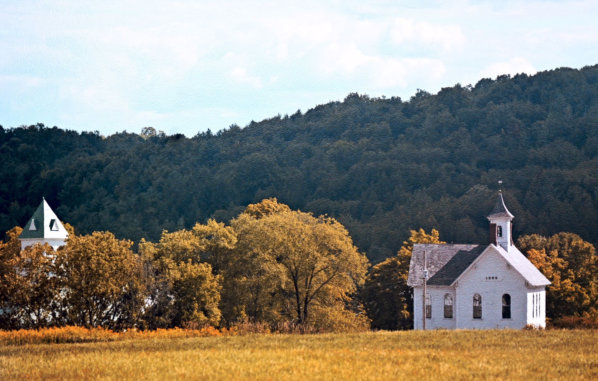 a small white church sits in the middle of a field
