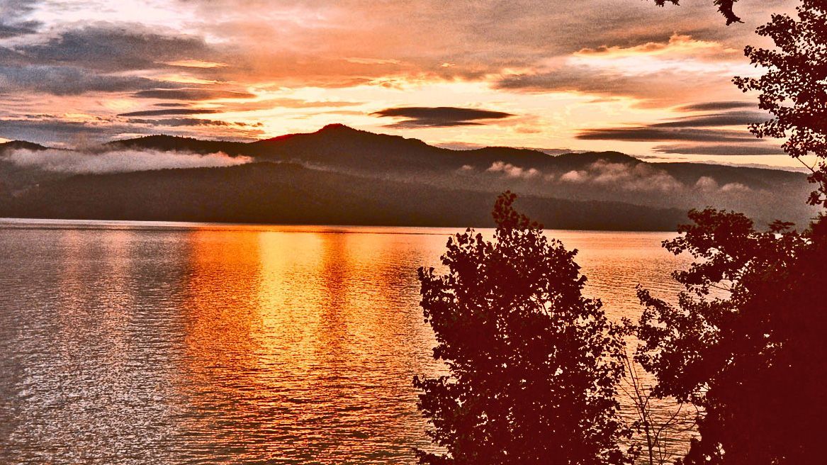 a sunset over  Lake Champlain with mountains in the background