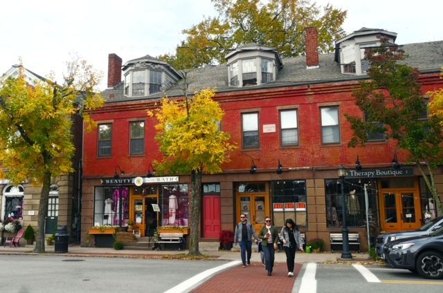 a group of people are crossing a street in front of a red brick building .