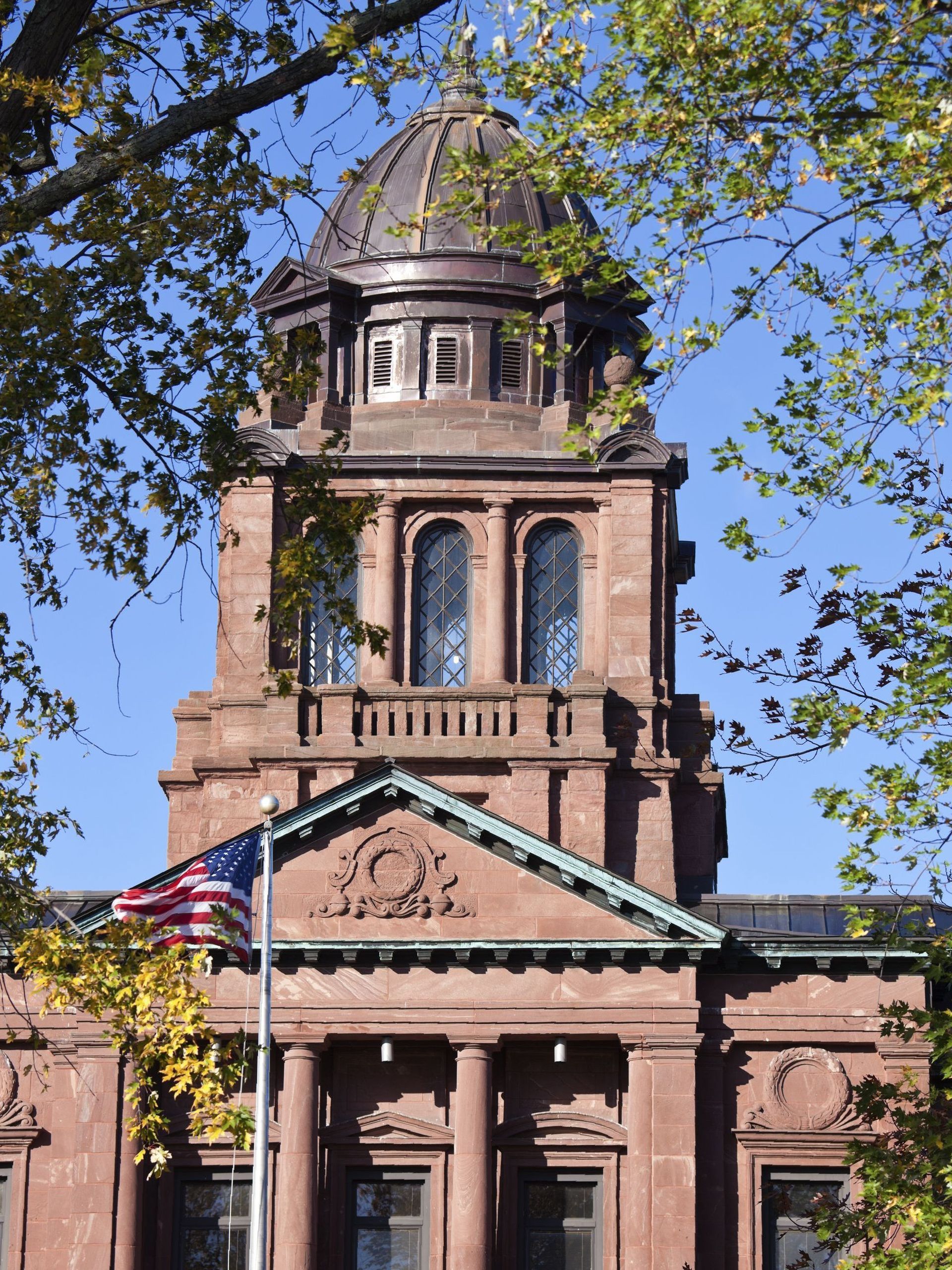 A wooden walkway leading to a gazebo overlooking a body of water at sunset.
