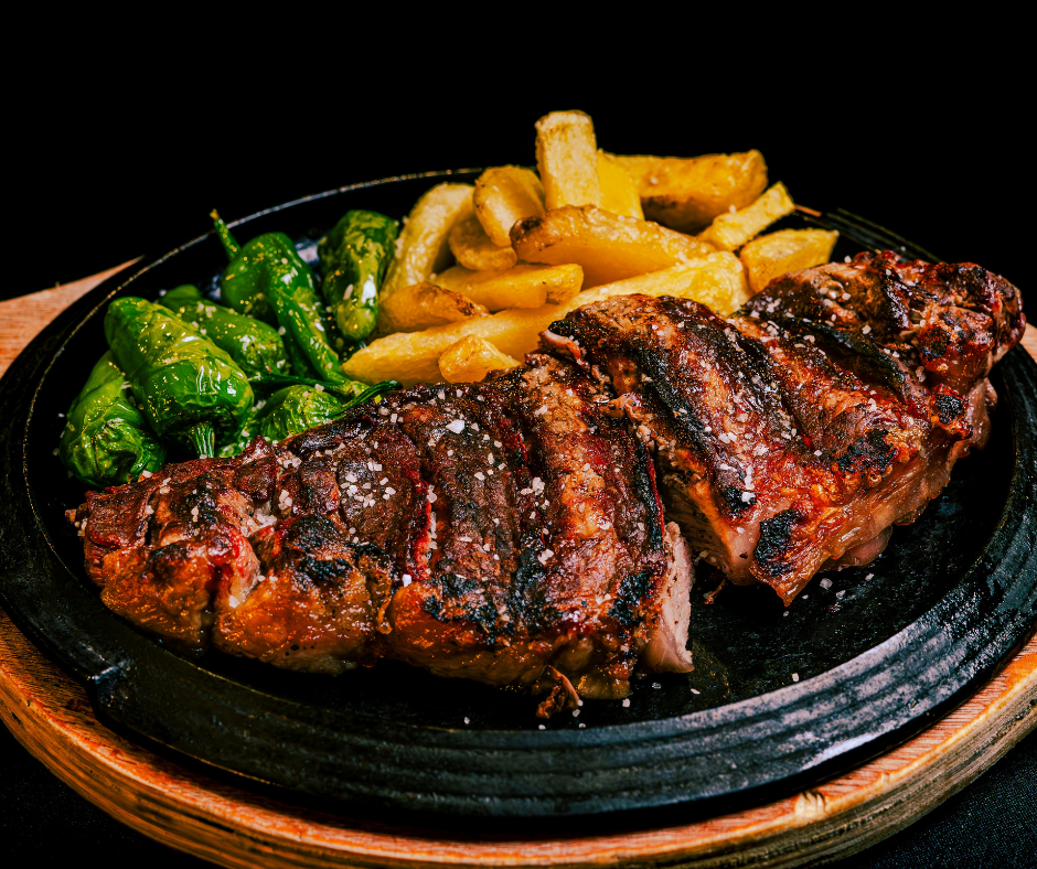 A steak with french fries and green peppers on a plate.
