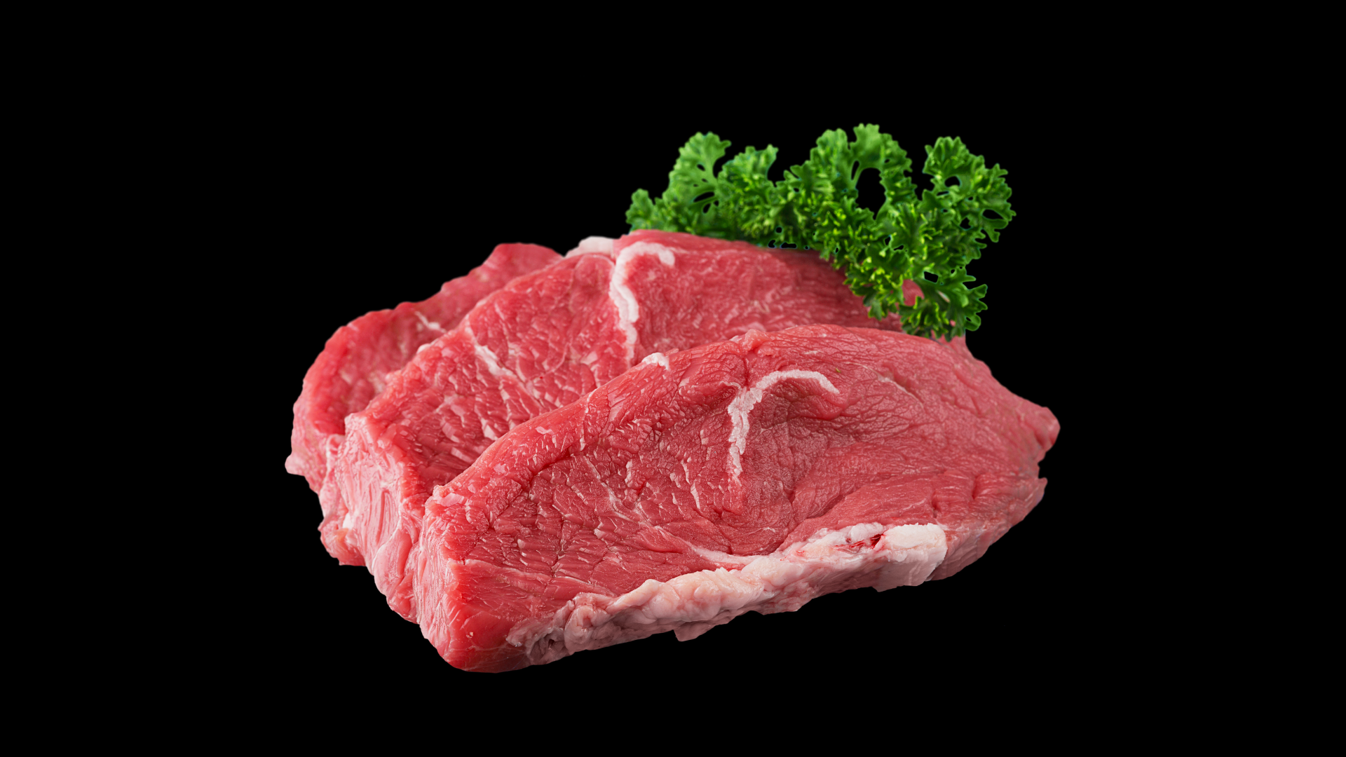 A piece of raw beef with parsley on a black background.