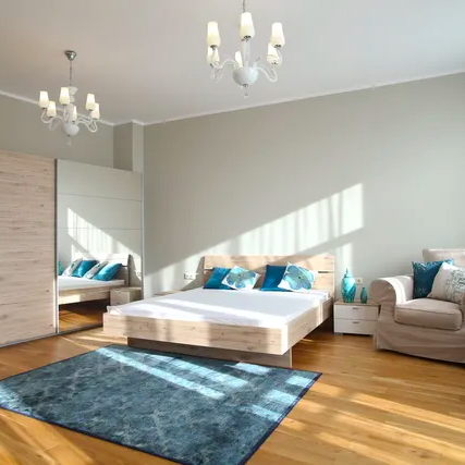 A bedroom with a bed , chair , rug and mirror.