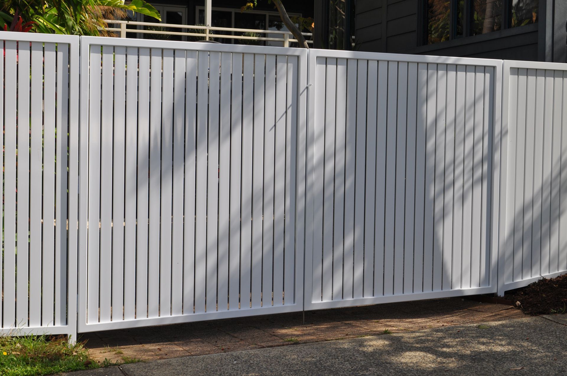 A white wooden fence is sitting in front of a house — Fabricator In Coffs Harbour, NSW