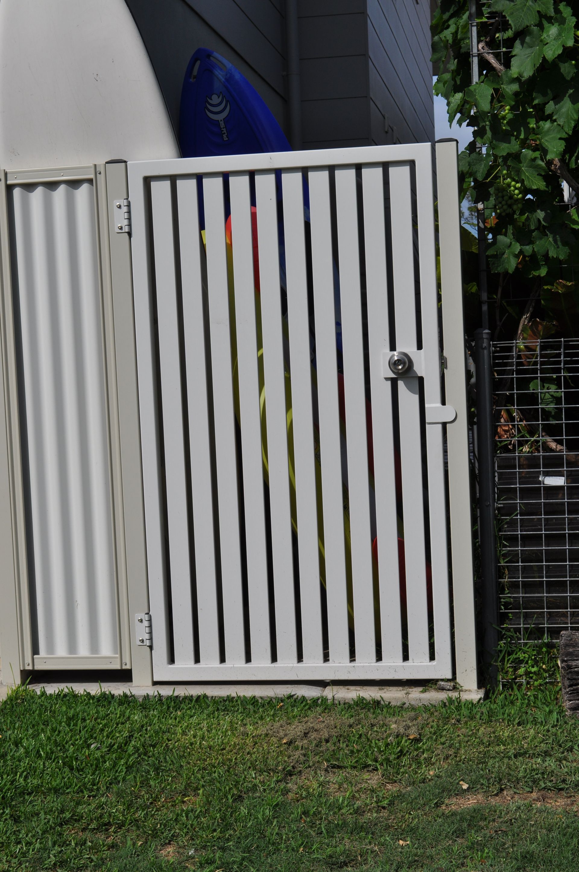 A white gate is sitting in the grass next to a building — Fabricator In Coffs Harbour, NSW