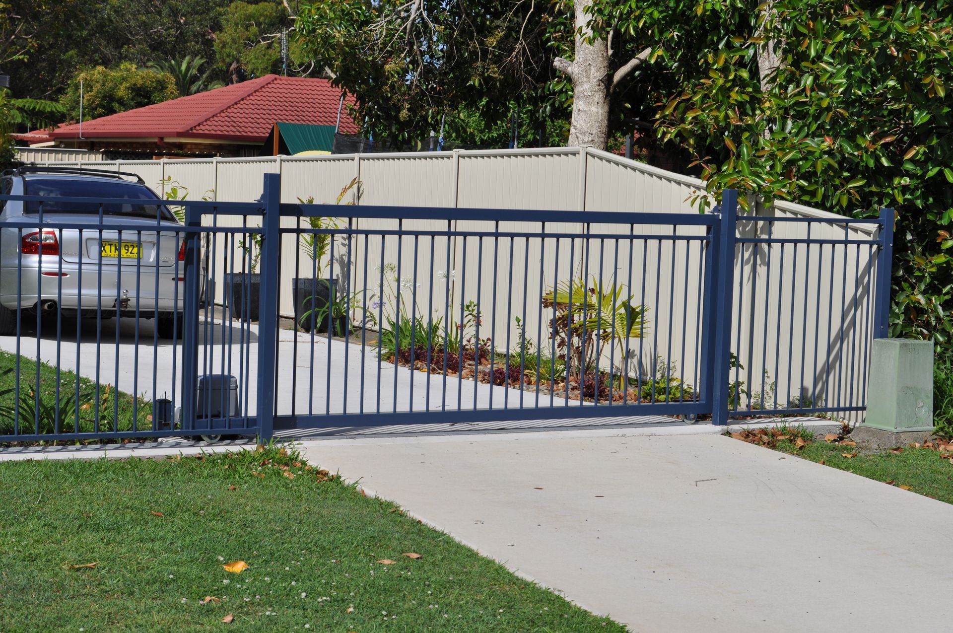 A car is parked in a driveway behind a fence with a license plate that says nz — Fabricator In Coffs Harbour, NSW