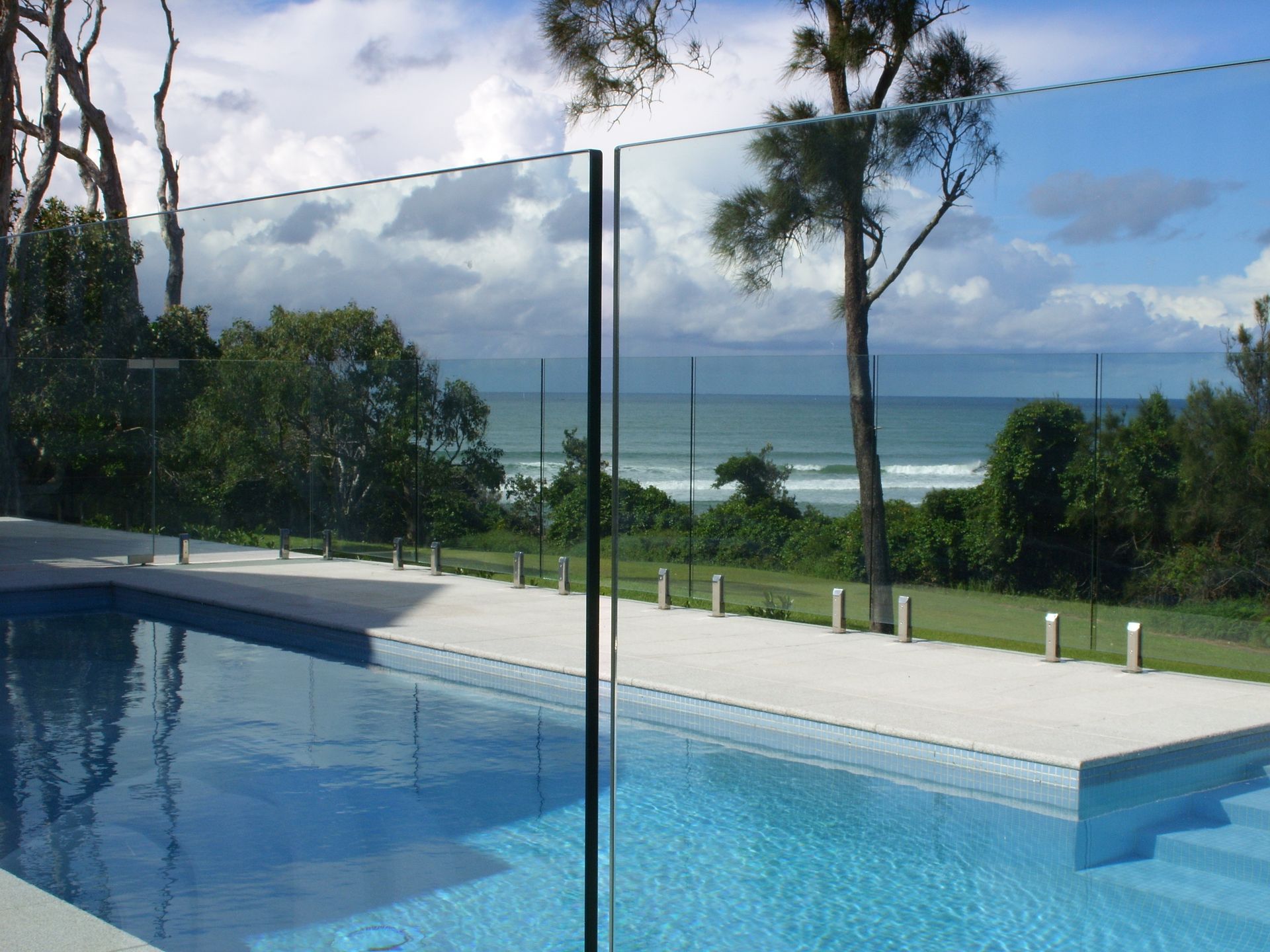 A swimming pool with a glass fence and a view of the ocean — Fabricator In Coffs Harbour, NSW