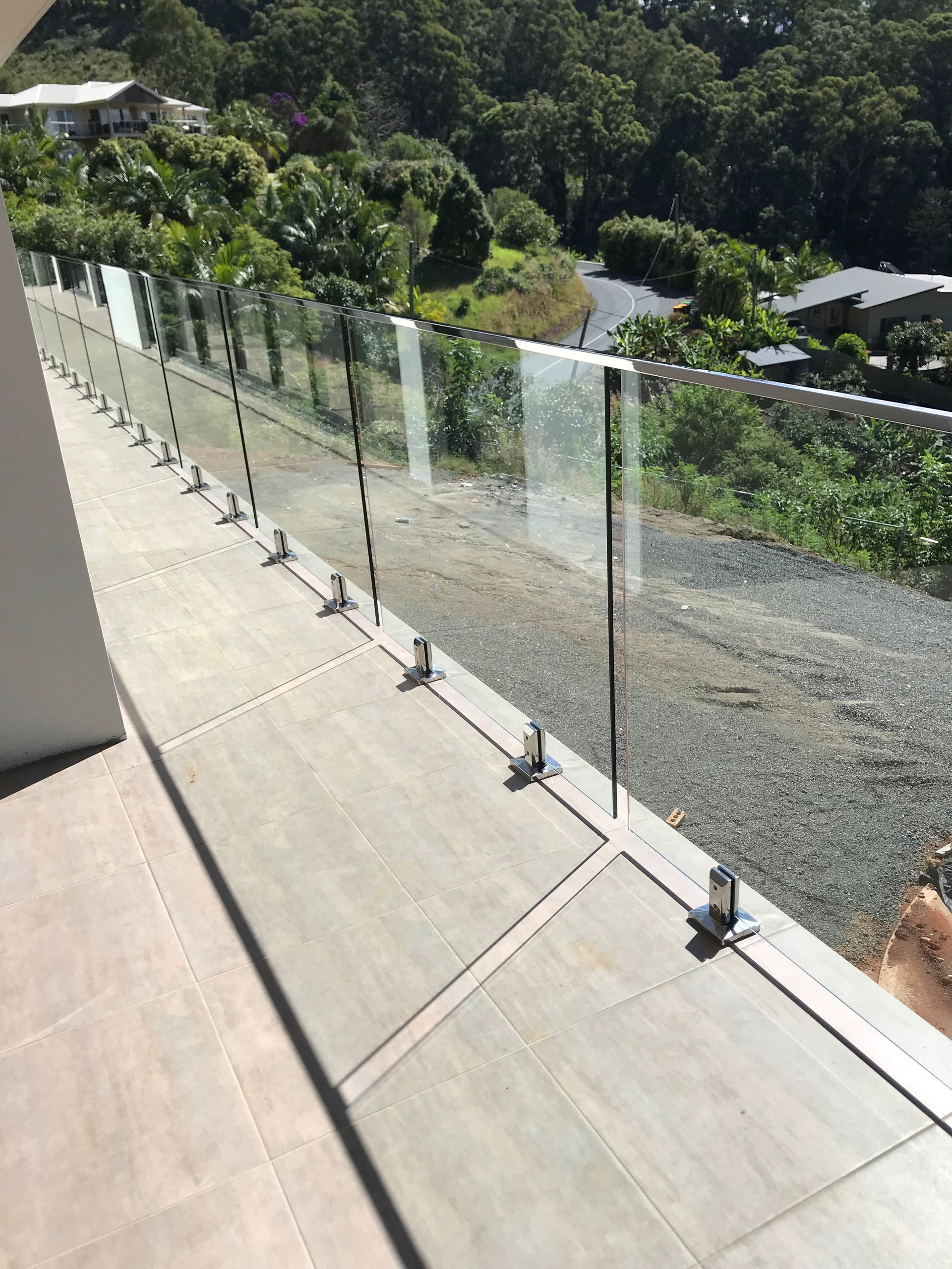 A balcony with a glass railing and a view of a forest — Fabricator In Coffs Harbour, NSW