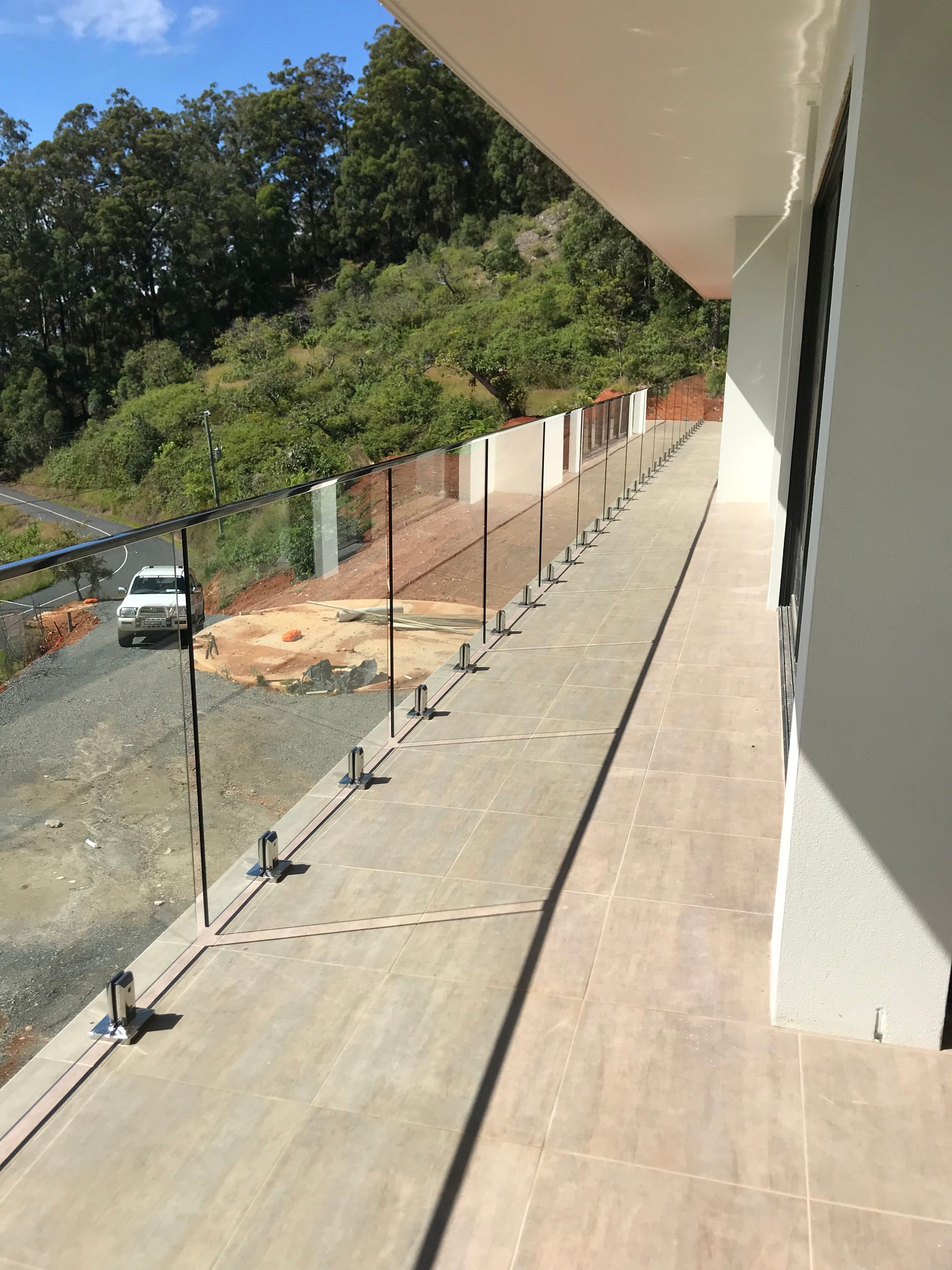 A balcony with a glass railing is being built on the side of a building — Fabricator In Coffs Harbour, NSW