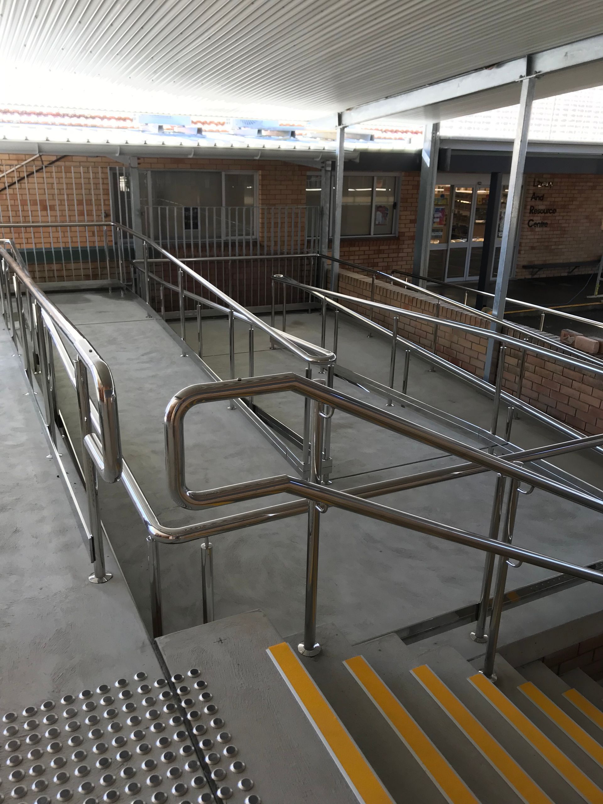A staircase with a stainless steel railing and yellow steps — Fabricator In Coffs Harbour, NSW