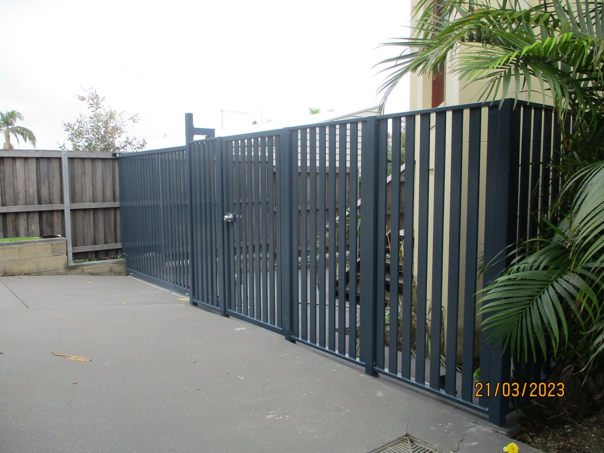 A fence with a gate and a wooden fence behind it — Fabricator In Coffs Harbour, NSW
