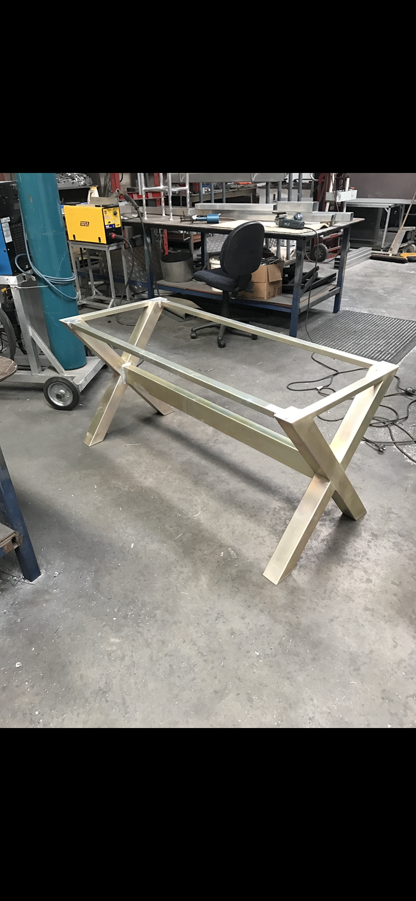 A wooden table with a glass top is sitting on a concrete floor in a factory — Fabricator In Coffs Harbour, NSW
