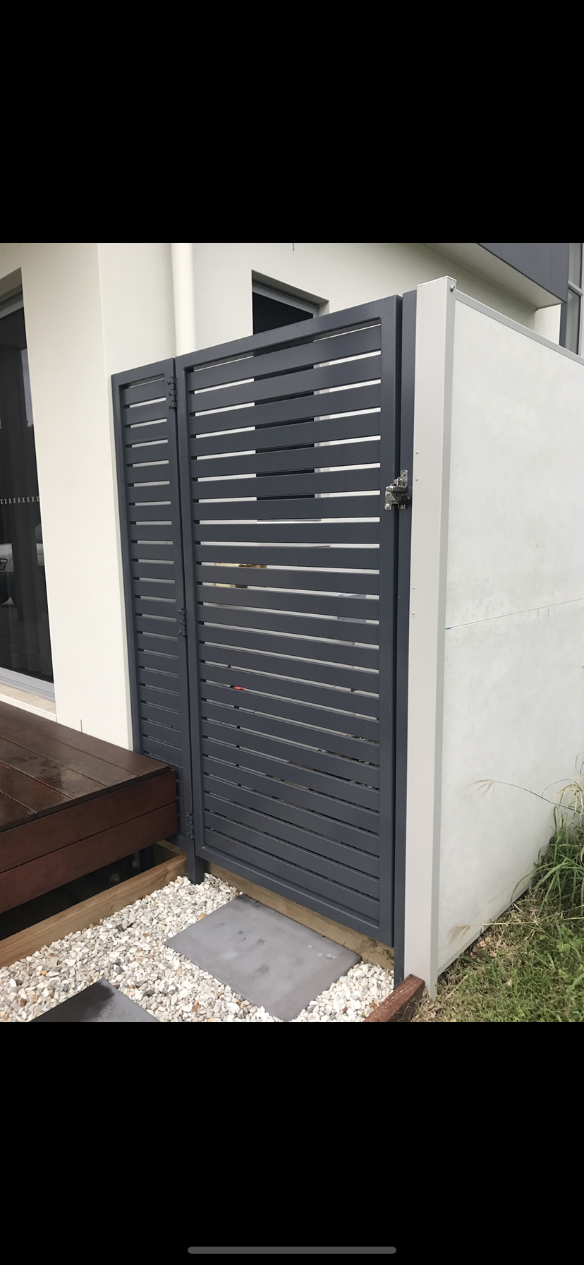 A black gate is sitting next to a white building — Fabricator In Coffs Harbour, NSW