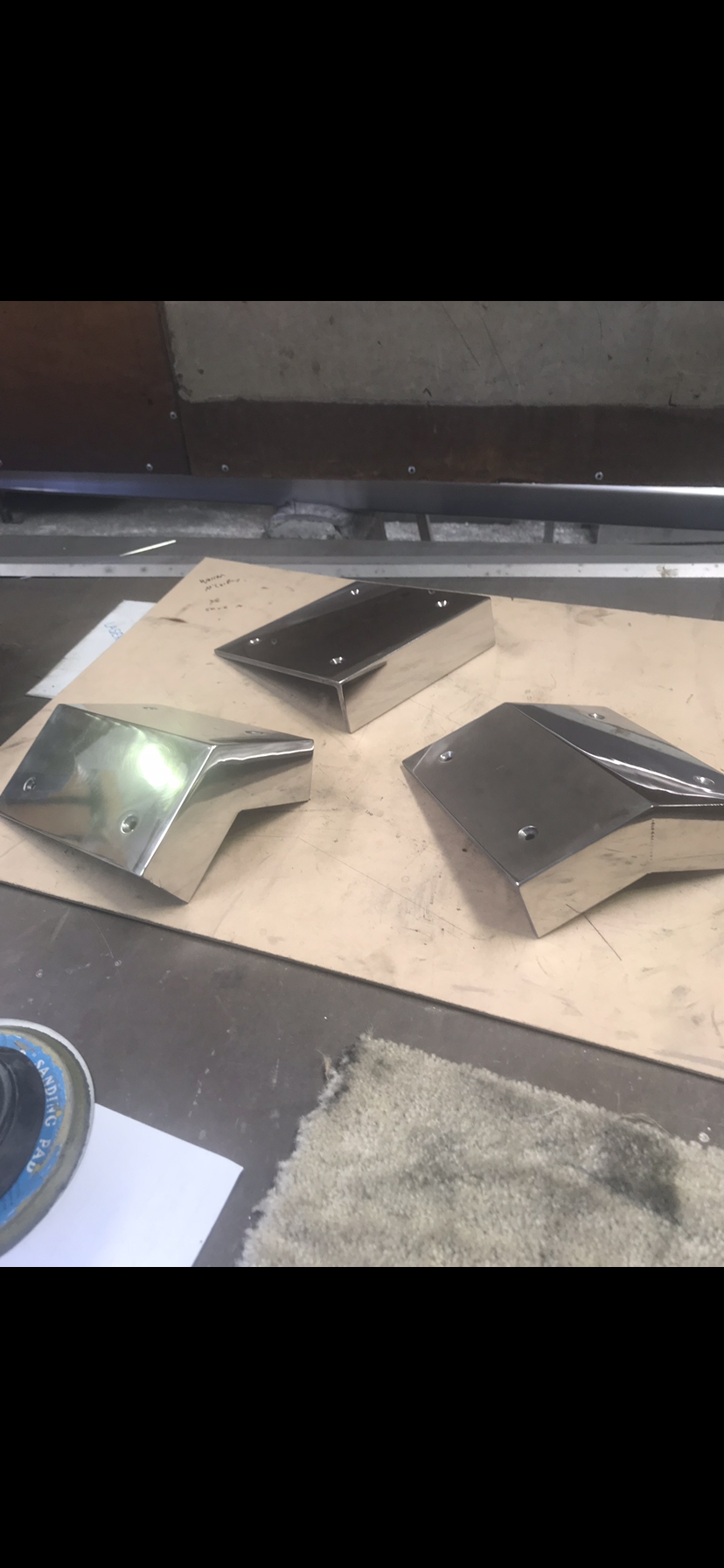 Three metal pieces are sitting on top of a wooden table — Fabricator In Coffs Harbour, NSW