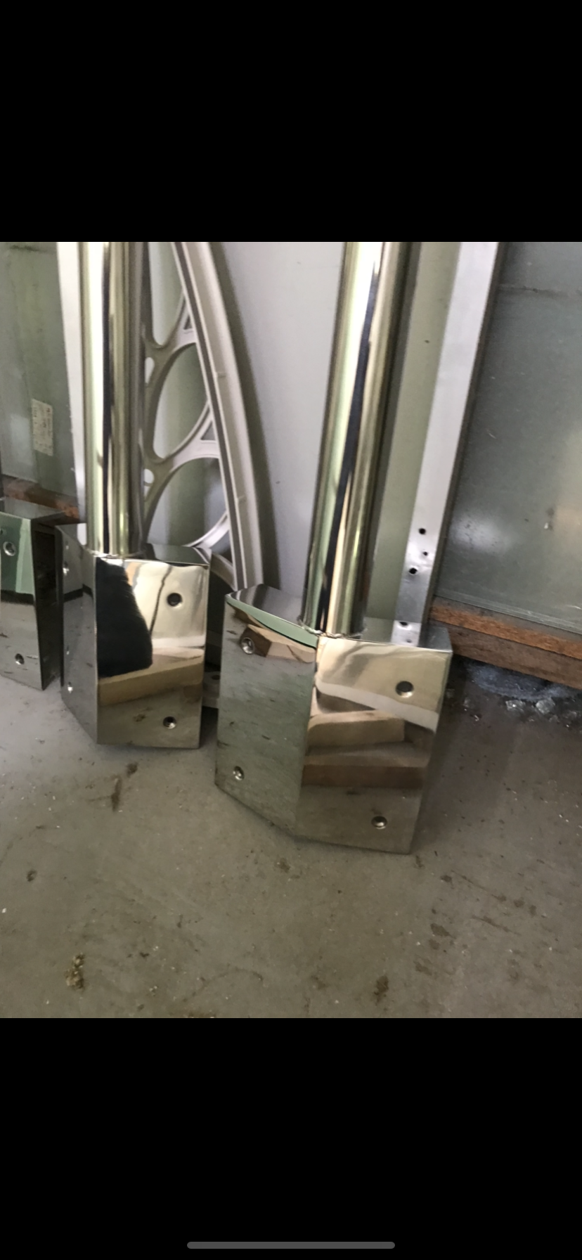 A pair of stainless steel brackets are sitting on top of a wooden table — Fabricator In Coffs Harbour, NSW