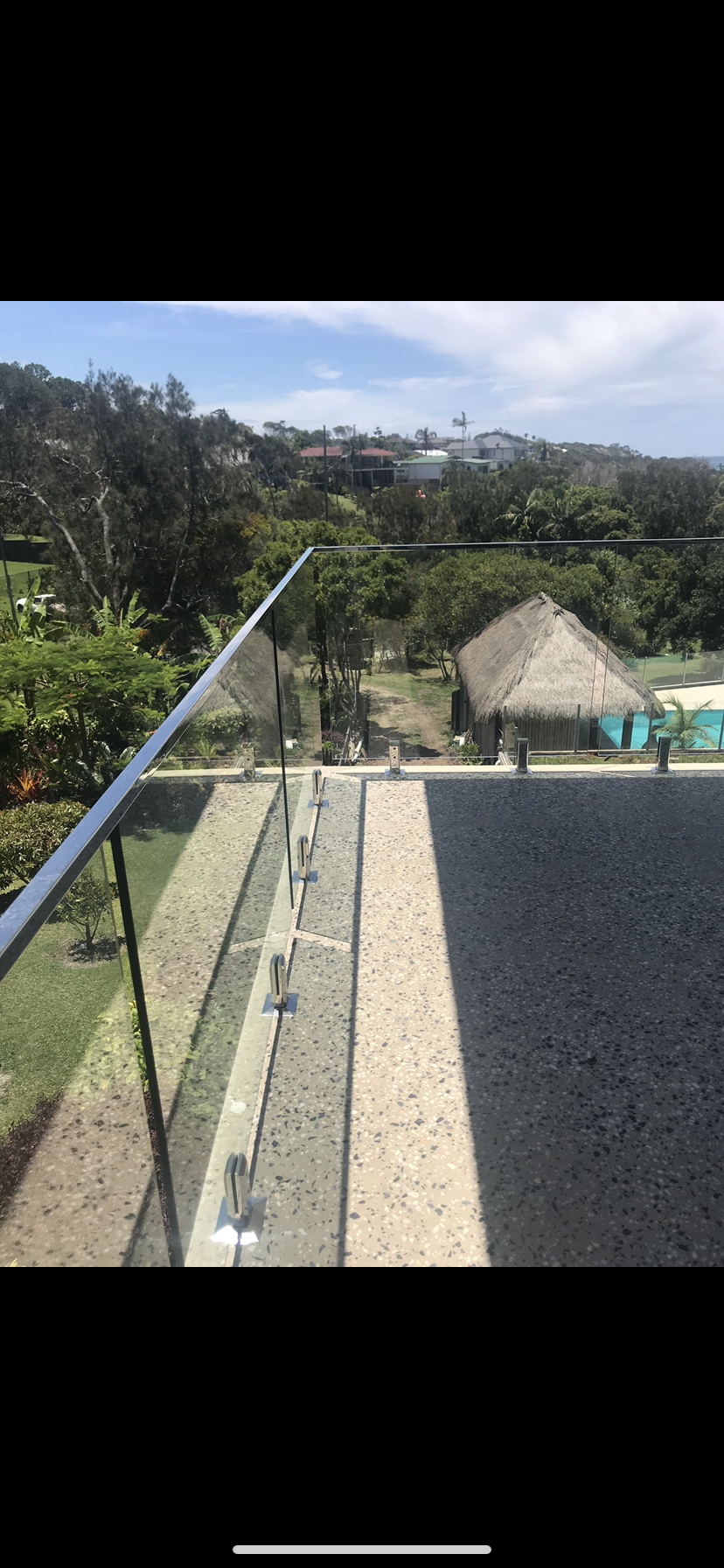 A balcony with a glass railing overlooking a lush green field — Fabricator In Coffs Harbour, NSW