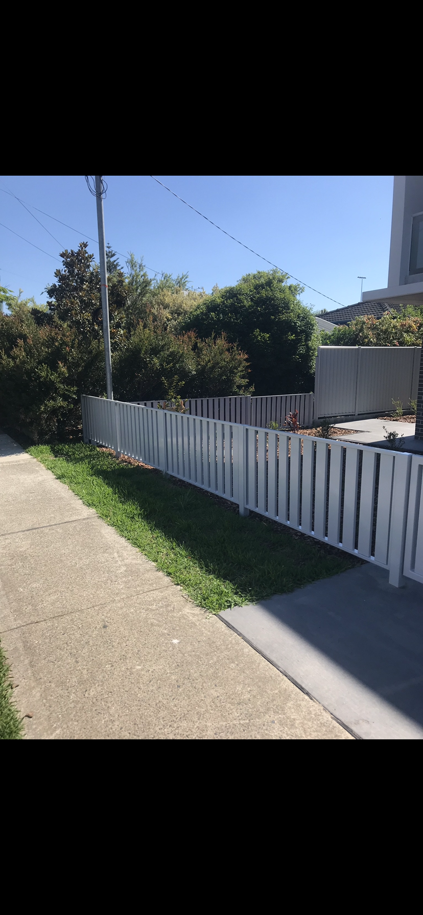 A white picket fence along a sidewalk next to a house — Fabricator In Coffs Harbour, NSW