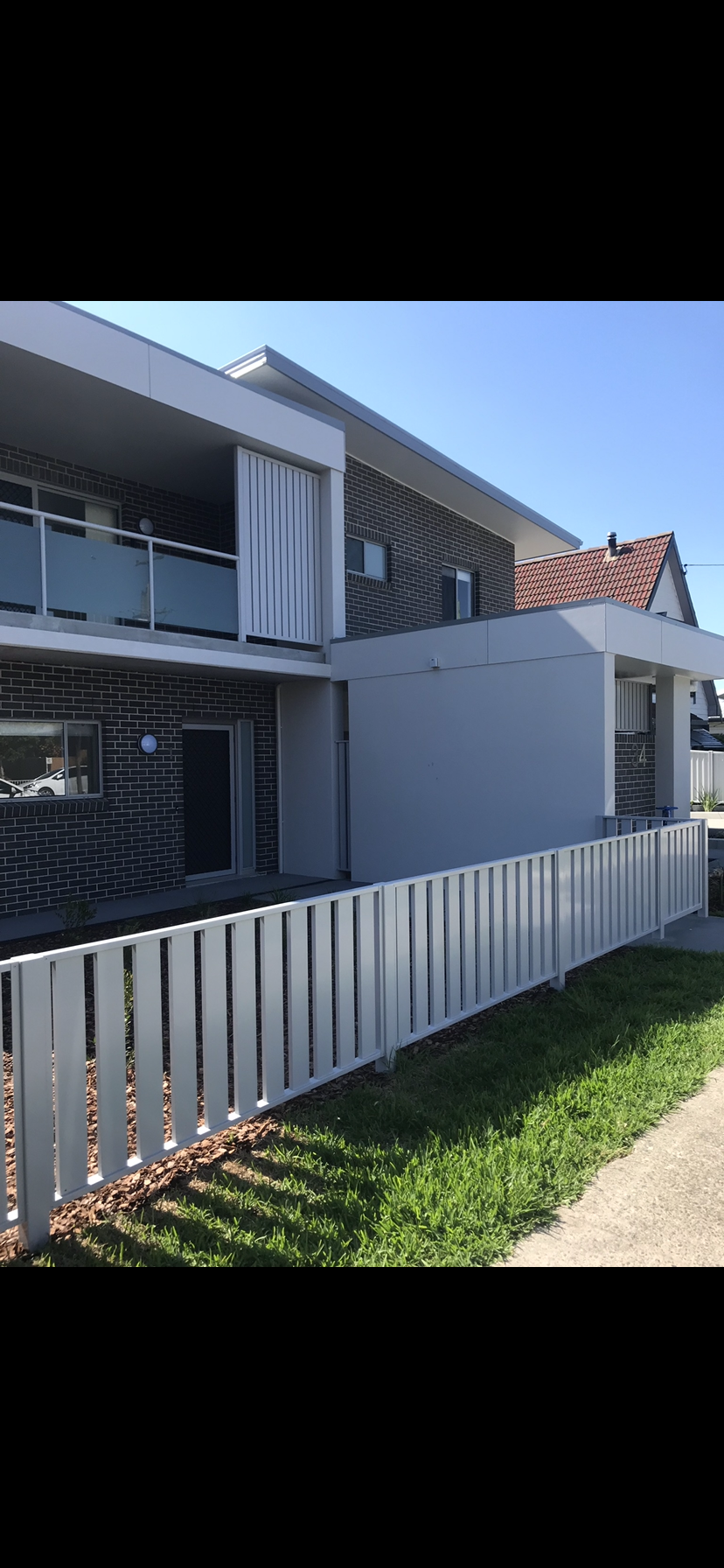 A white picket fence is in front of a house — Fabricator In Coffs Harbour, NSW