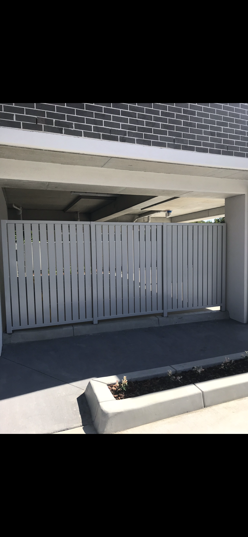 A white fence is sitting in front of a brick building — Fabricator In Coffs Harbour, NSW
