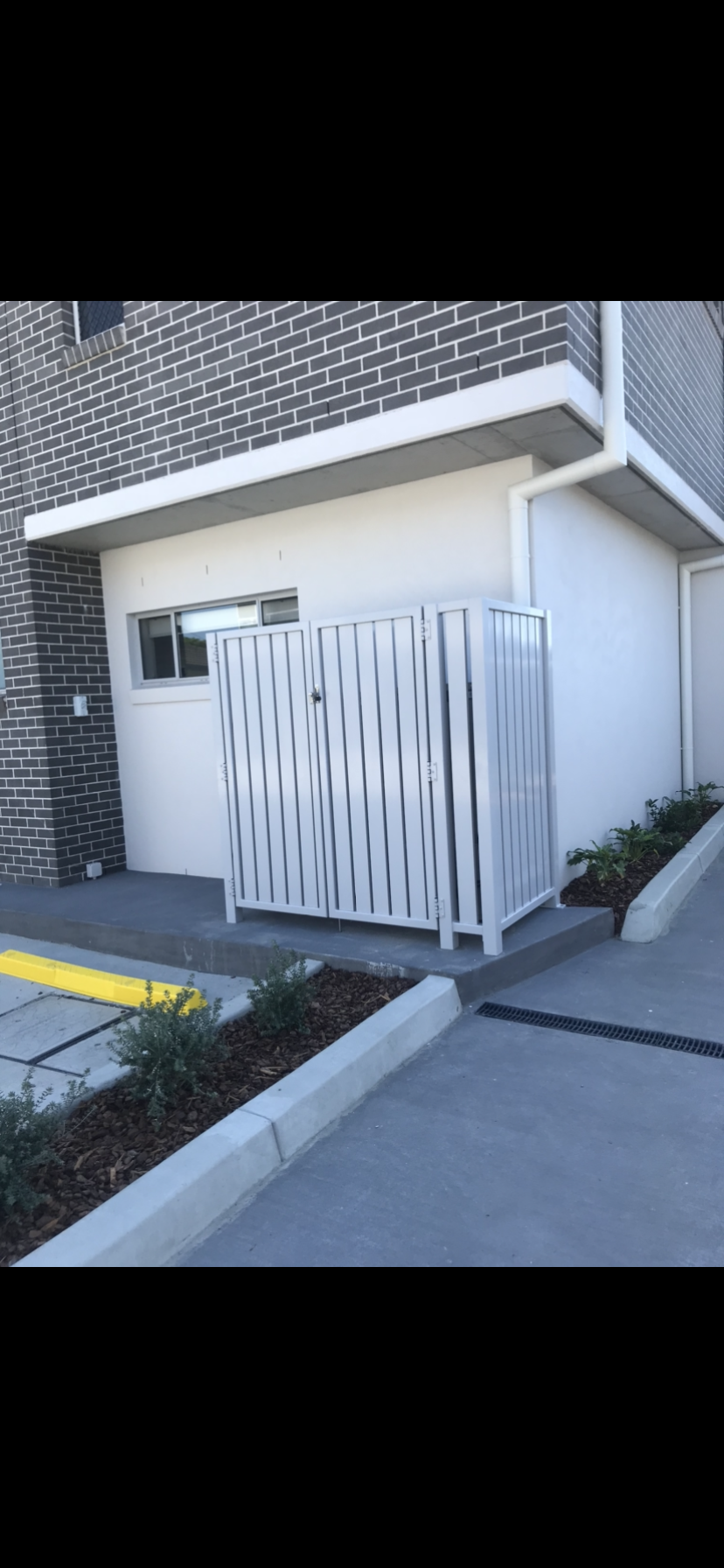 A white fence is in front of a brick building — Fabricator In Coffs Harbour, NSW