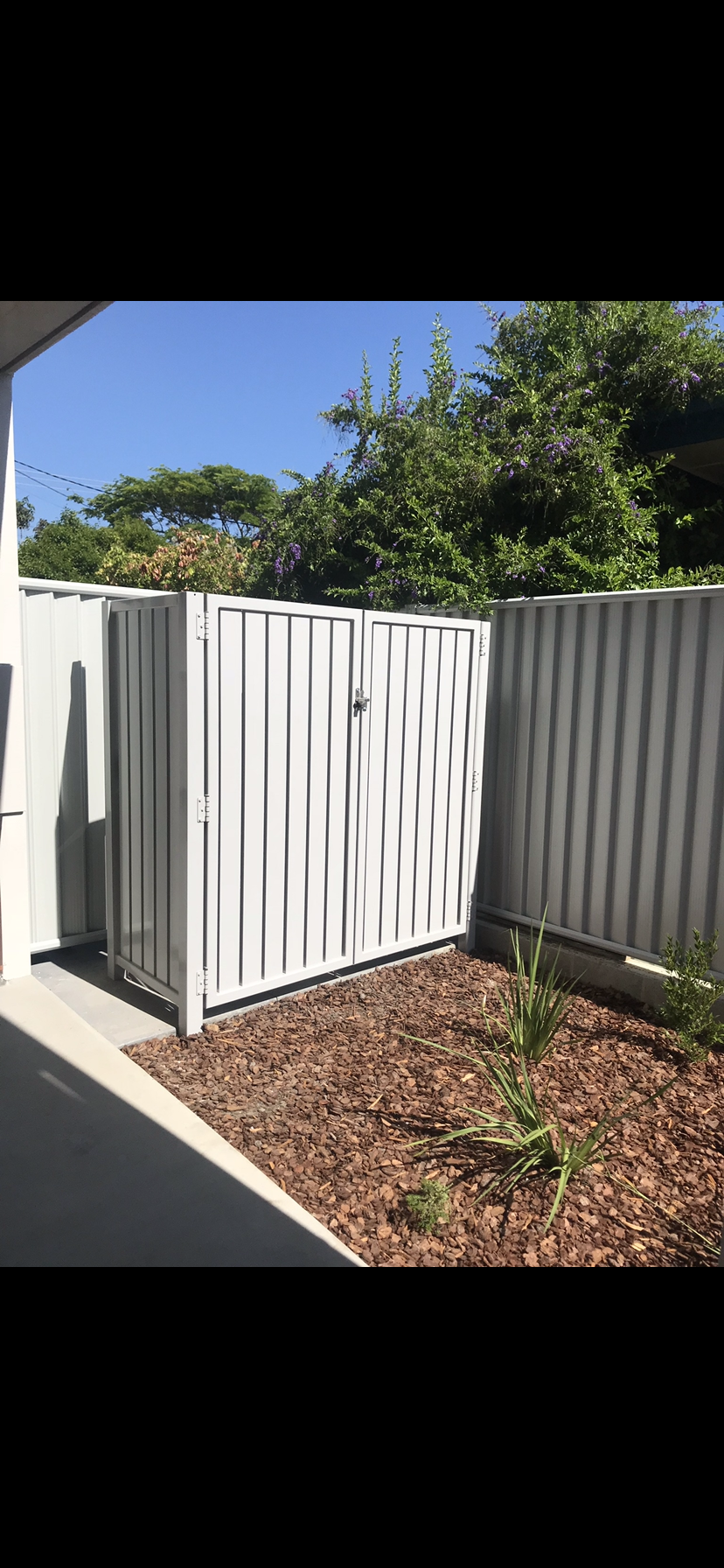 A white fence with a gate in the backyard of a house — Fabricator In Coffs Harbour, NSW