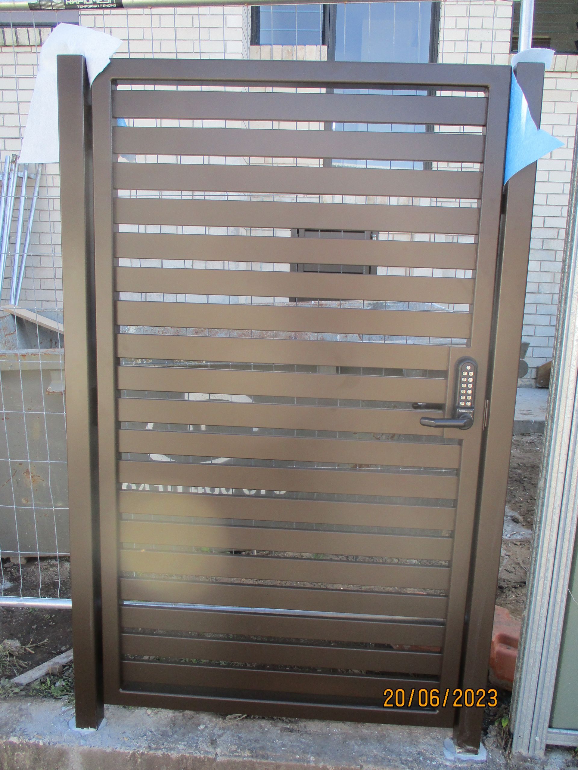A wooden gate with a lock on it is sitting next to a brick wall — Fabricator In Coffs Harbour, NSW
