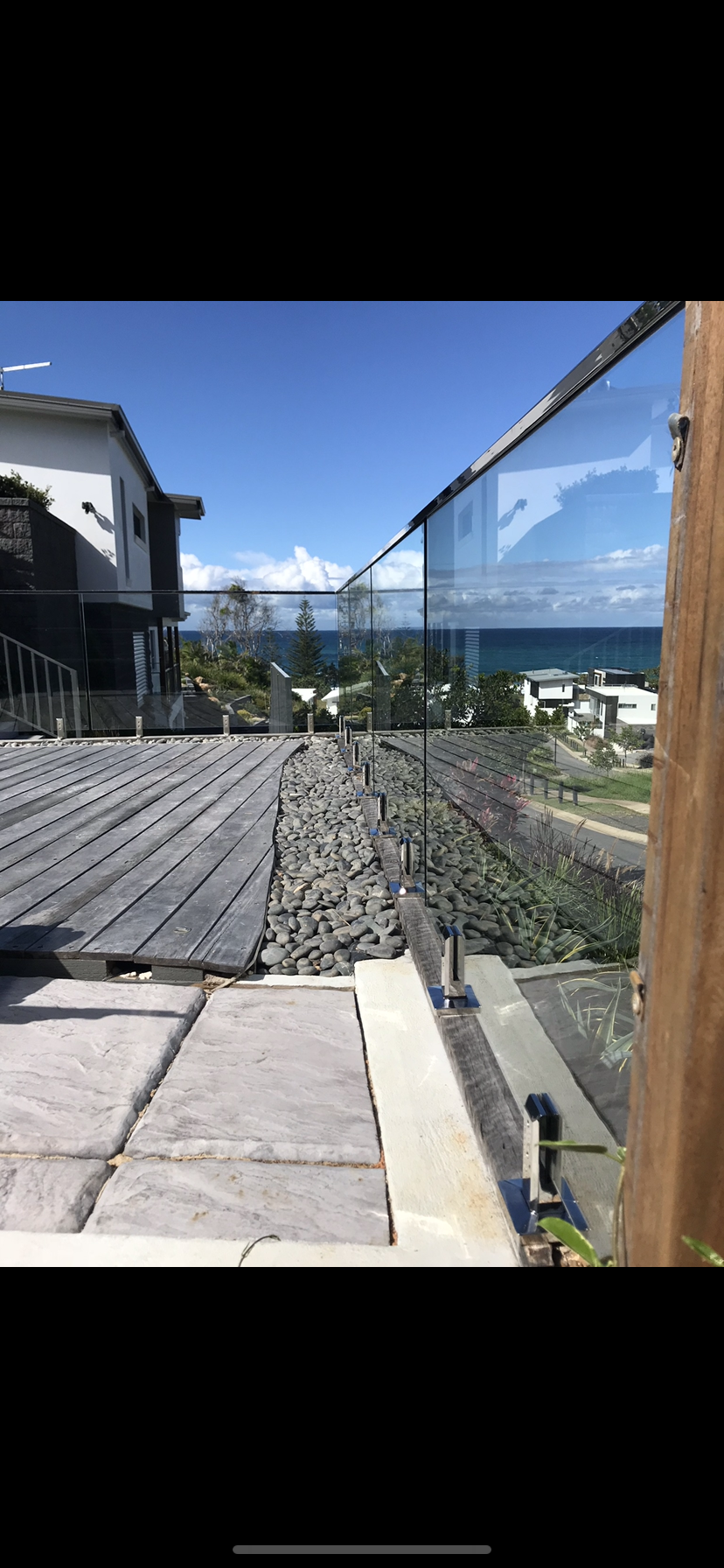 A view of the ocean from a balcony with a glass railing — Fabricator In Coffs Harbour, NSW