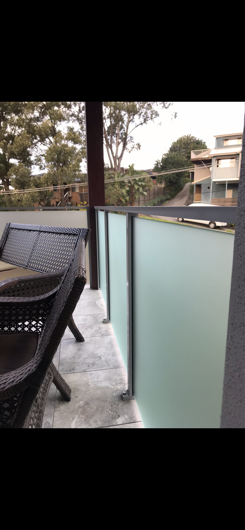 A balcony with a table and chairs and a glass railing — Fabricator In Coffs Harbour, NSW
