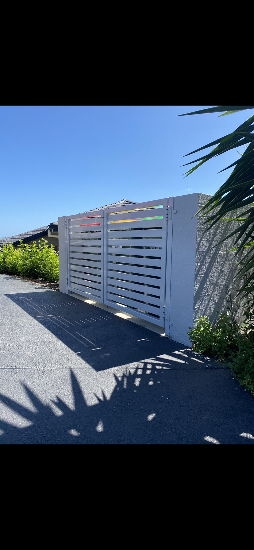 A white fence is sitting on the side of a road next to a palm tree — Fabricator In Coffs Harbour, NSW