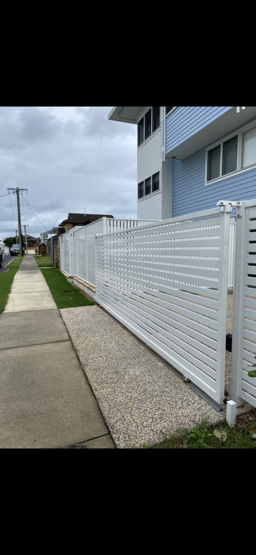 A white fence along a sidewalk next to a building. — Fabricator In Coffs Harbour, NSW
