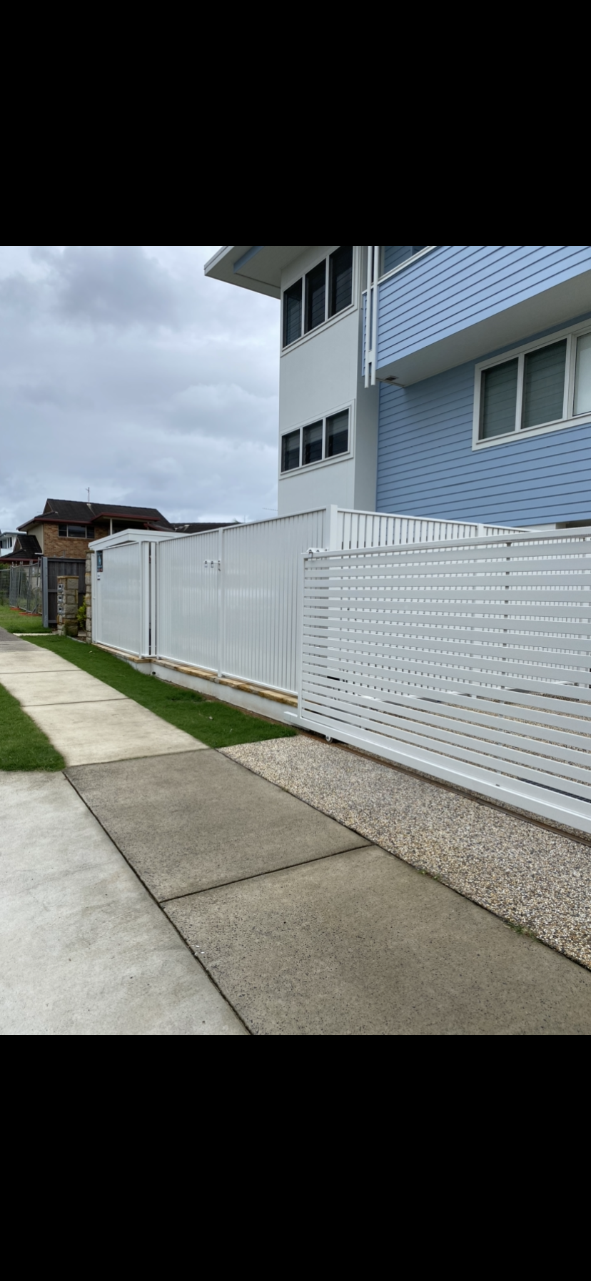 A white fence is along the sidewalk in front of a building — Fabricator In Coffs Harbour, NSW