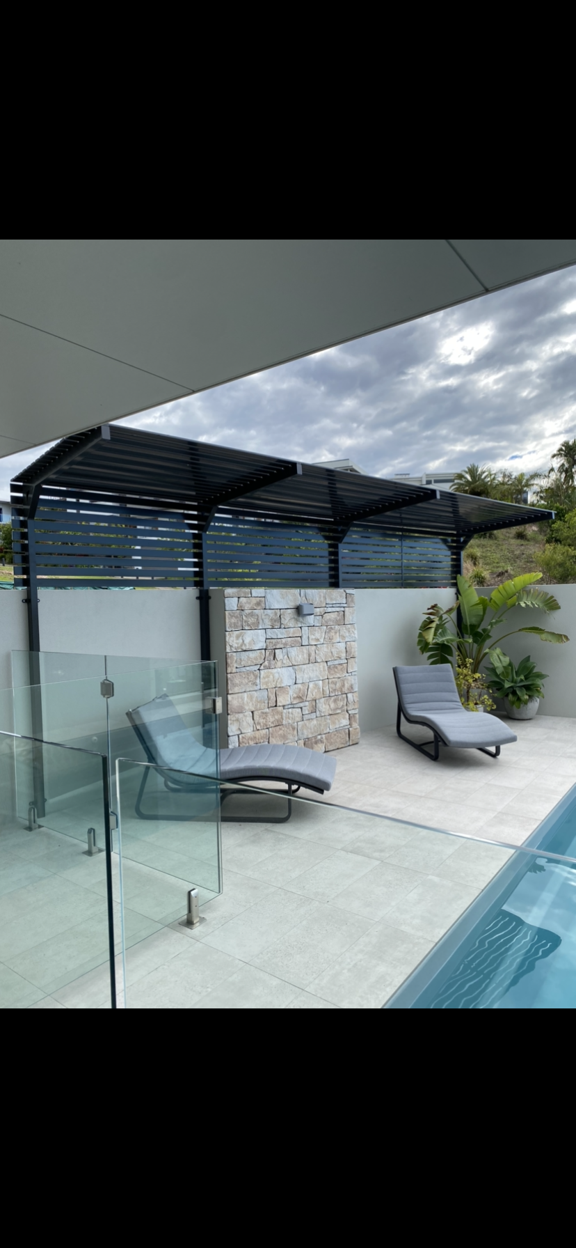 A swimming pool with a pergola and chairs next to it — Fabricator In Coffs Harbour, NSW