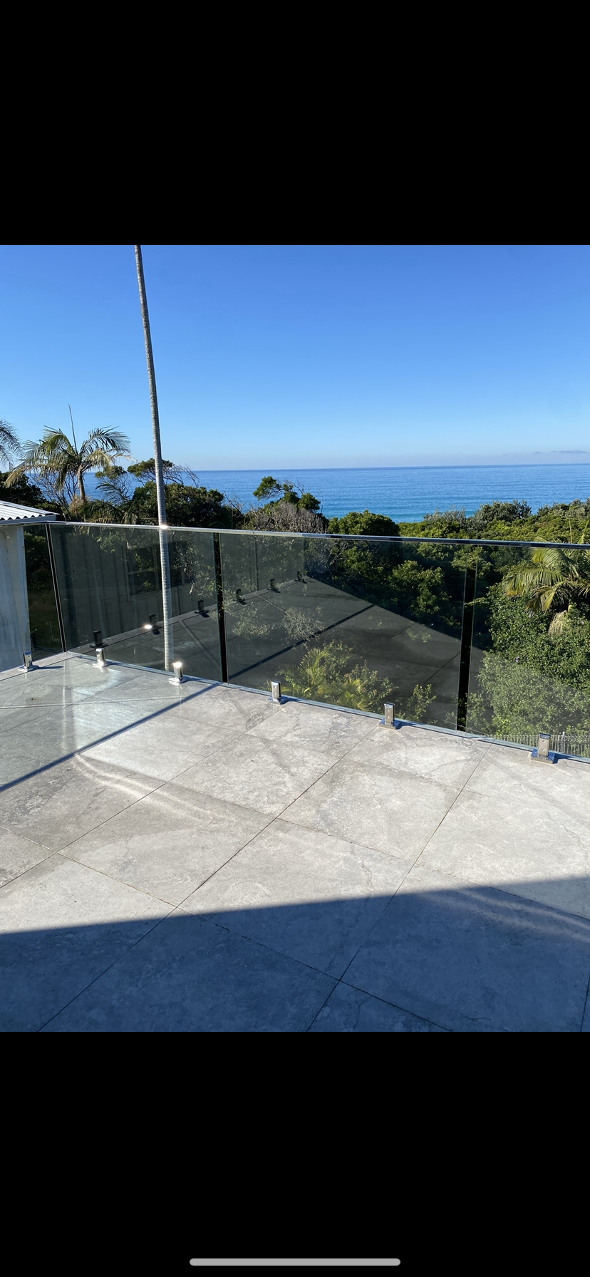 A balcony with a glass railing overlooking the ocean — Fabricator In Coffs Harbour, NSW