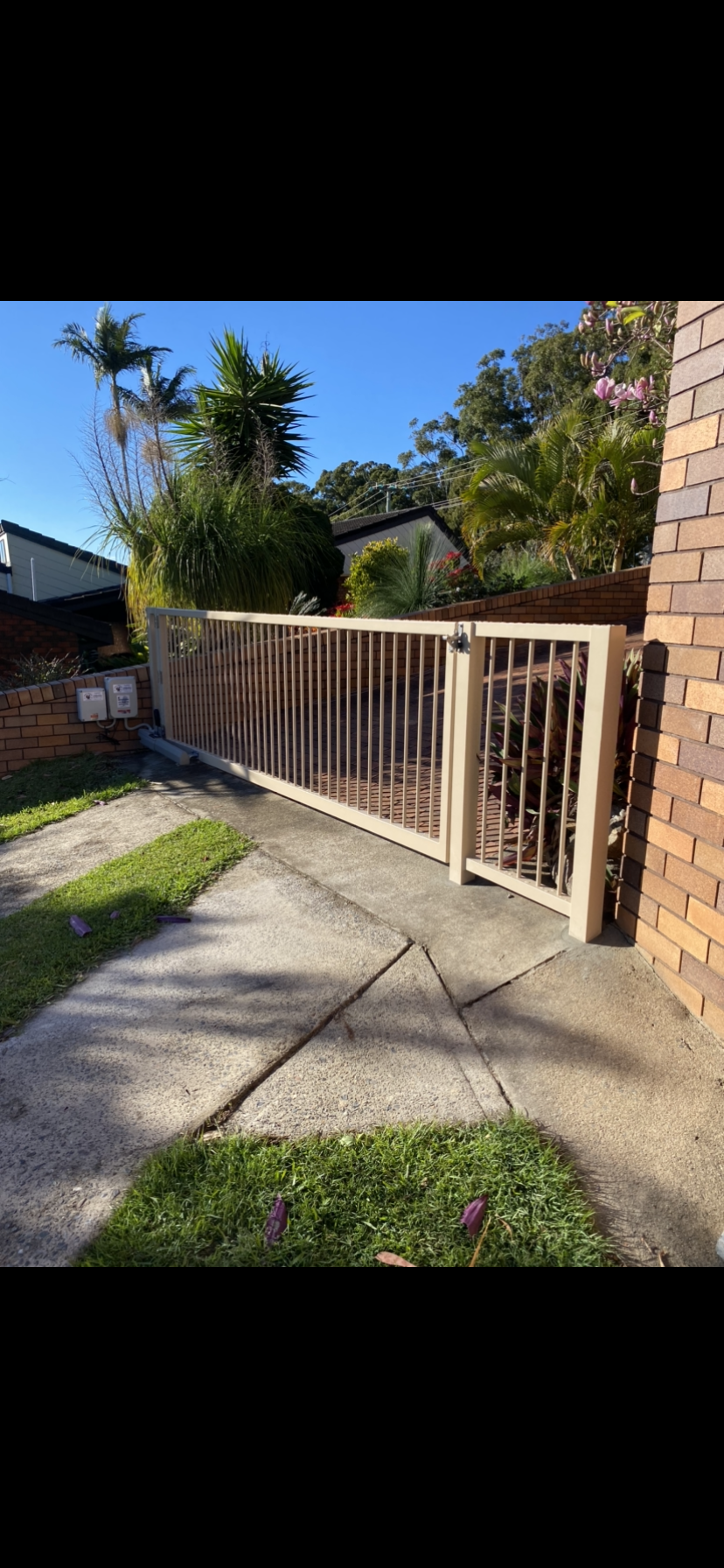 A white fence surrounds a brick building next to a sidewalk — Fabricator In Coffs Harbour, NSW