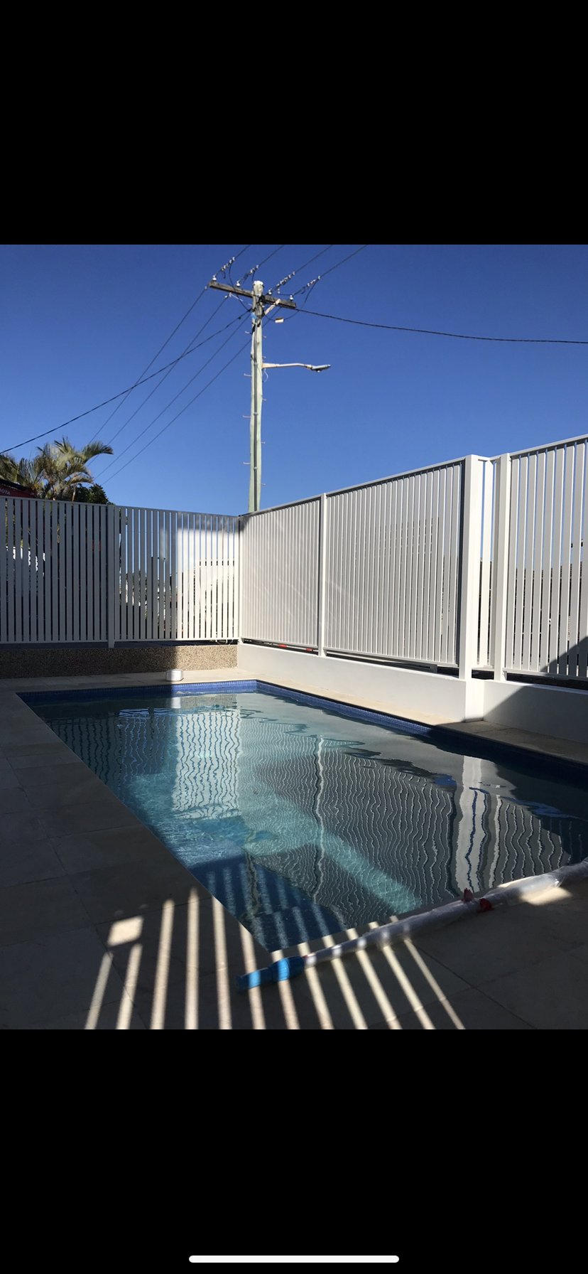 A large swimming pool surrounded by a white fence — Fabricator In Coffs Harbour, NSW