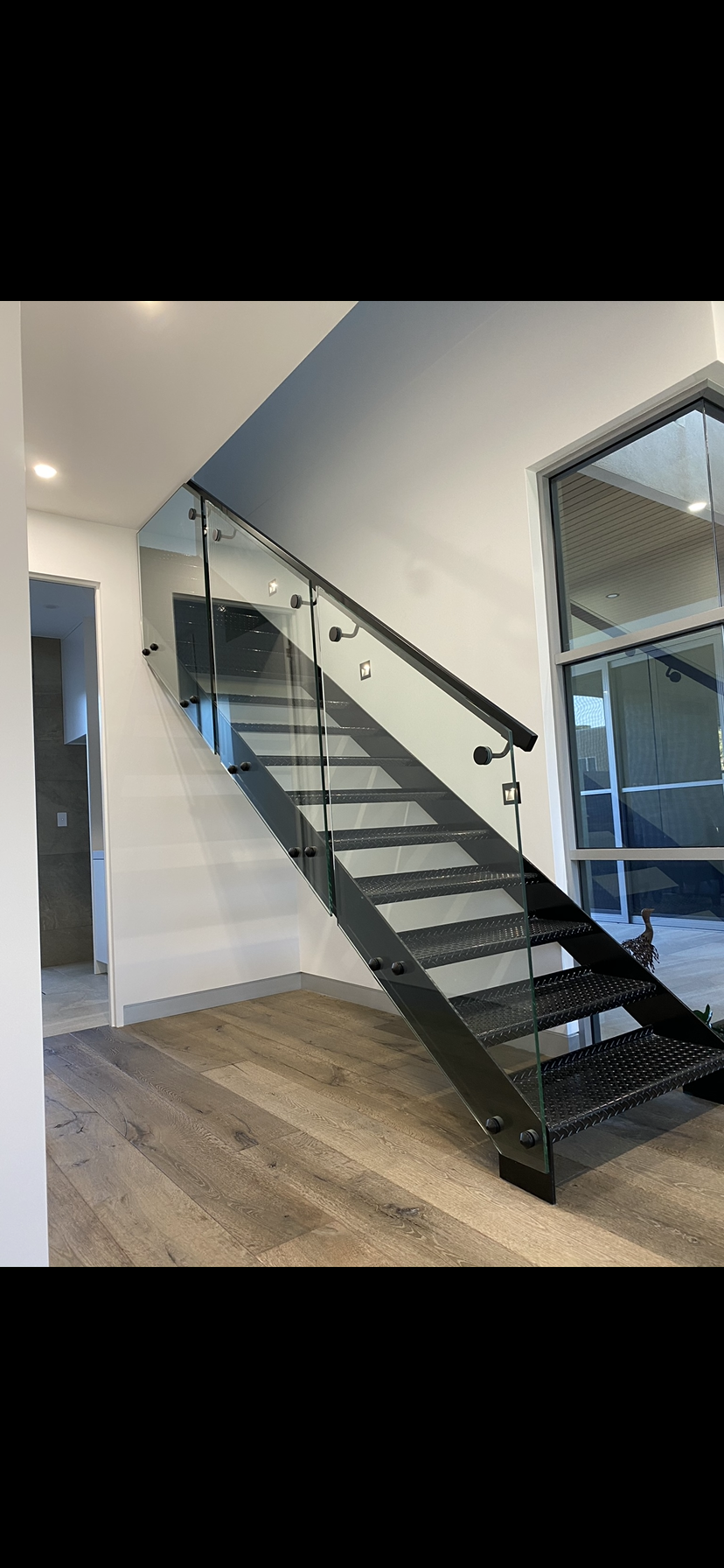 A black staircase with a glass railing in a room — Fabricator In Coffs Harbour, NSW