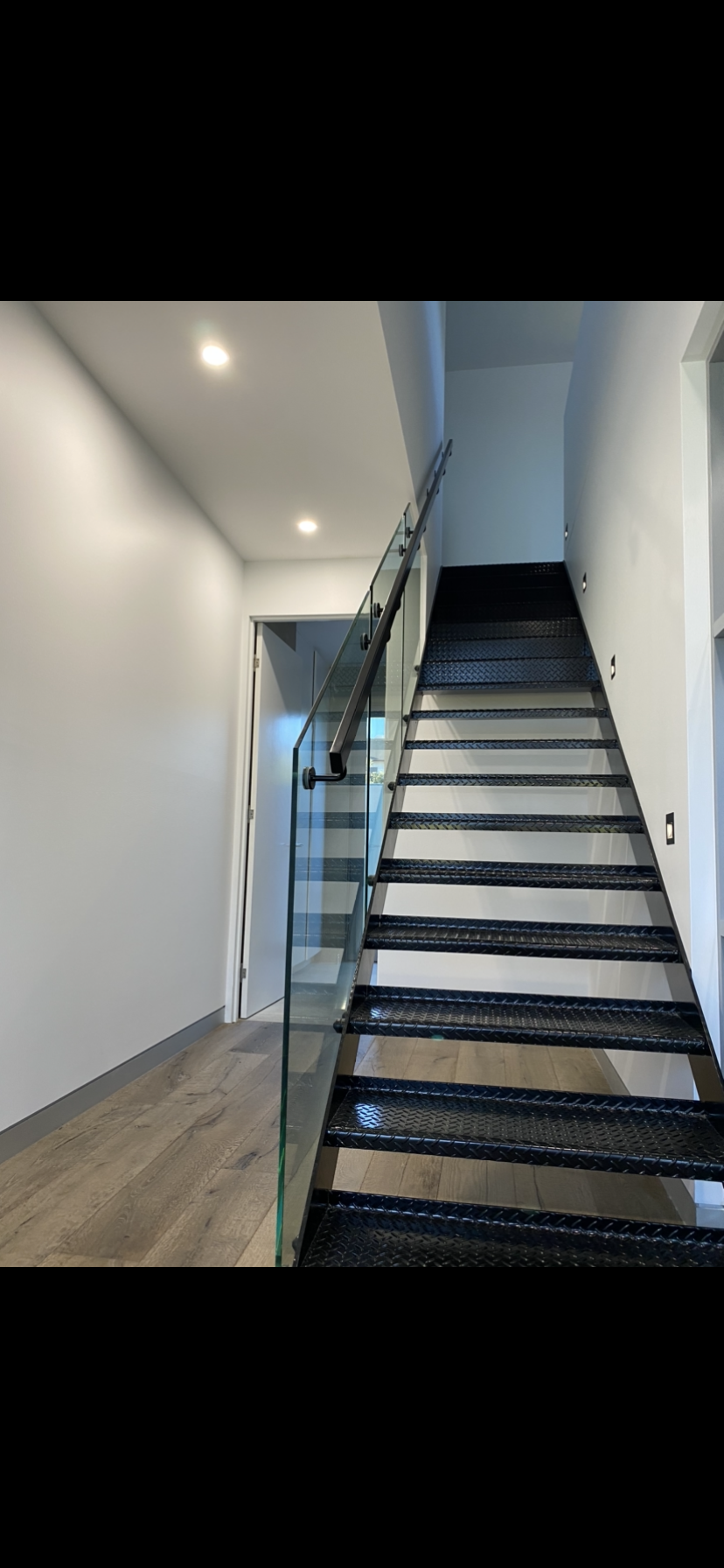 A staircase with black steps and a glass railing in a hallway — Fabricator In Coffs Harbour, NSW