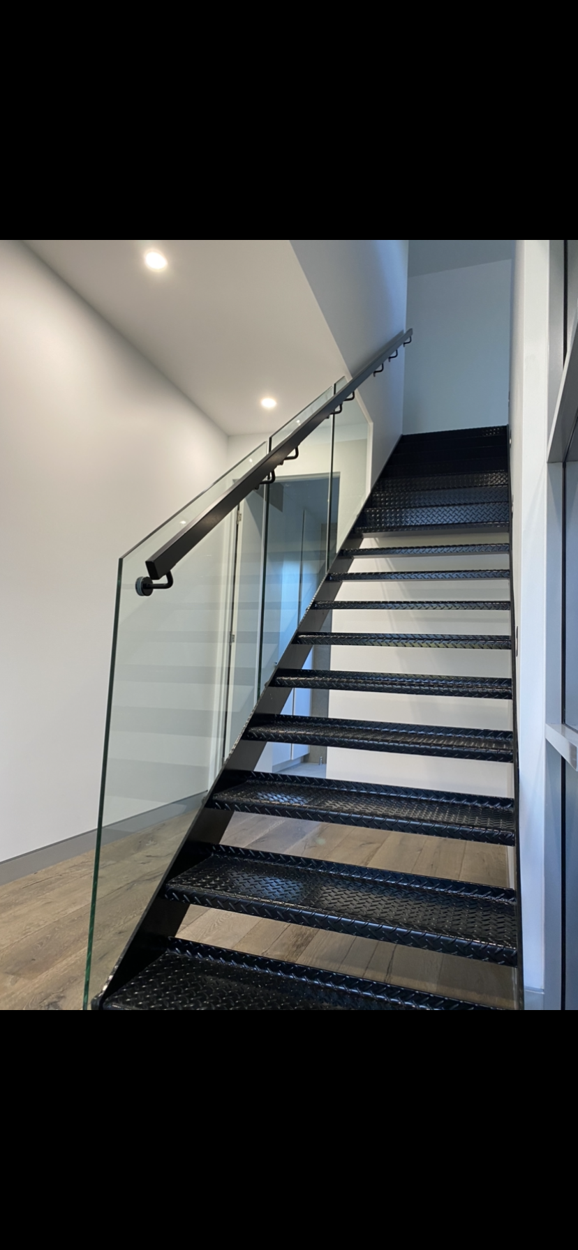 A black staircase with a glass railing in a room. — Fabricator In Coffs Harbour, NSW